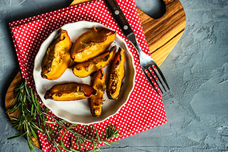 Baked pumpkin slice with rosemary on plate with copy spaceの写真素材