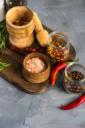 Organic spices like pepper, rosemary, different types of salt on rustic background