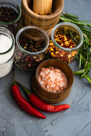 Organic spices like pepper, rosemary, different types of salt on rustic backgroundの写真素材