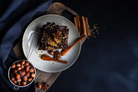 Dark chocolate pieces crushed on dark wooden table, spices like a cinnamon and anise star as a culinary concept with copy space, top viewの写真素材