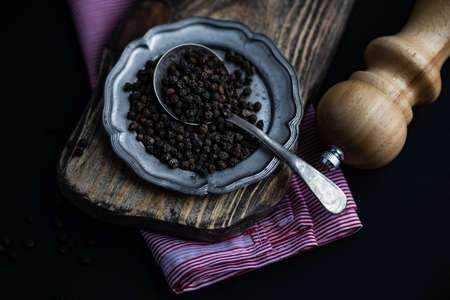 Cooking concept with vintage plate full of pepper corn on dark rustic background with copy spaceの写真素材
