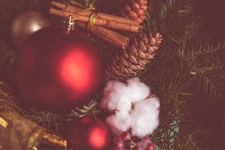 Christmas card concept on rustic dark wooden background with bright balls, fir tree and cotton headsの写真素材