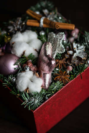Christmas card concept on rustic dark wooden background with bright balls, fir tree and cotton headsの写真素材