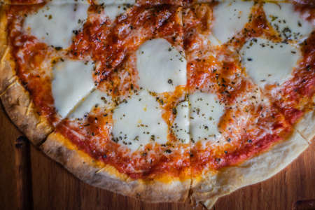 Italian pizza in slices on dark wooden cutting board with copy spaceの写真素材