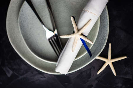 Summer table setting with white sea stars on concrete background with copy space
