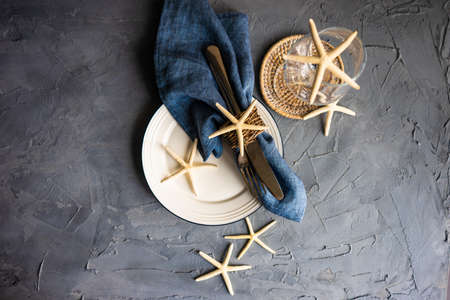 Summer table setting with white sea stars on concrete background with copy space