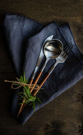 Modern metal cutlery and napkin set with rosemary on dark background with copy spaceの写真素材