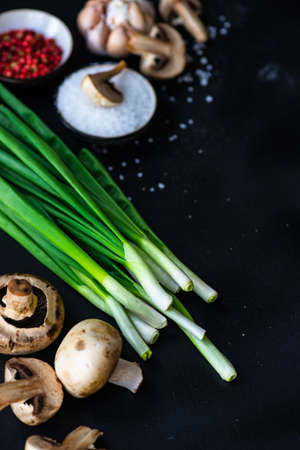Ingredients for cooking vegetable soup with mushrooms and onion on dark background with copy space