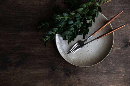Spring table setting for Easter holiday dinner with boxwood and colored eggs on wooden table with copy spaceの写真素材