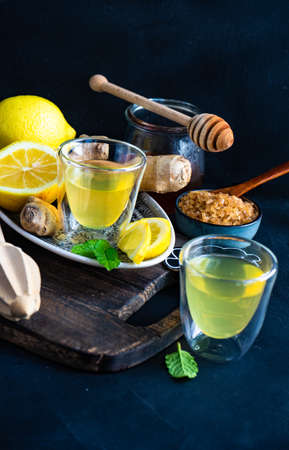Detox drink with organic lemon, ginger and mint on dark background with copy space