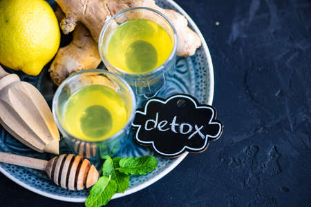 Detox drink with organic lemon, ginger and mint on dark background with copy space