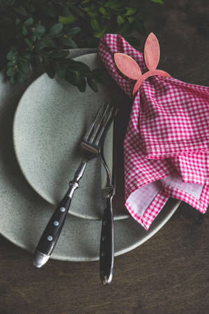 Spring table setting for Easter holiday dinner with boxwood and colored eggs on wooden table with copy spaceの写真素材