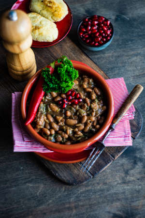 Traditional georgian red beans dish lobio with pomegranate on rustic table with copy space