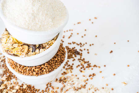 Organic superfood concept with raw  buckwheat, oatmeal and corn flour on wooden background