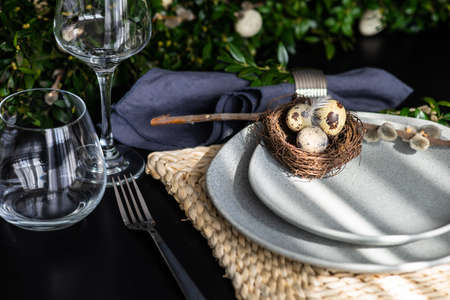 Festive table setting for Easter holiday dinner decorated with flowers and eggs