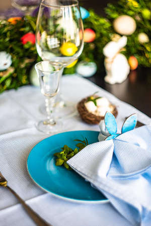 Festive table setting for Easter holiday dinner decorated with flowers and eggs