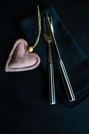 Stripped white and black cutlery with heart on black backgroundの写真素材