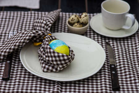 Festive table setting for Easter holiday dinner decorated with flowers and eggs