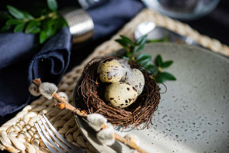 Festive table setting for Easter holiday dinner decorated with flowers and eggs
