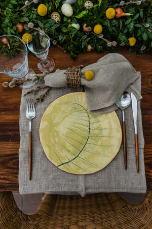 Festive table setting for Easter holiday dinner decorated with flowers and eggs