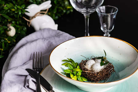 Festive table setting for Easter holiday dinner decorated with flowers and eggs