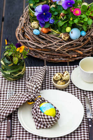Festive table setting for Easter holiday dinner decorated with flowers and eggs
