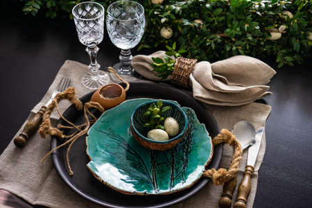 Festive table setting for Easter holiday dinner decorated with flowers and eggs