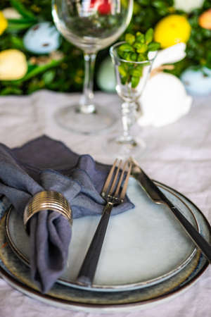 Festive table setting for Easter holiday dinner decorated with flowers and eggs