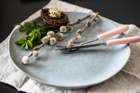 Festive table setting for Easter holiday dinner decorated with flowers and eggs