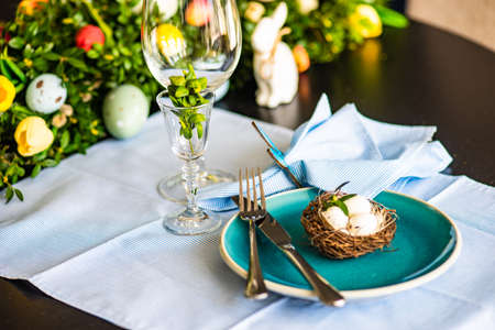 Festive table setting for Easter holiday dinner decorated with flowers and eggs