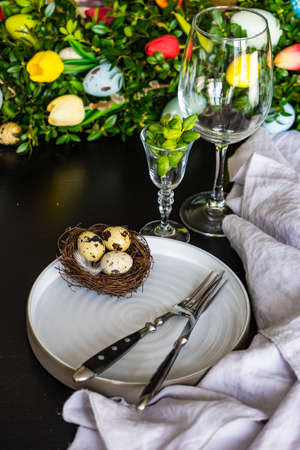Festive table setting for Easter holiday dinner decorated with flowers and eggs