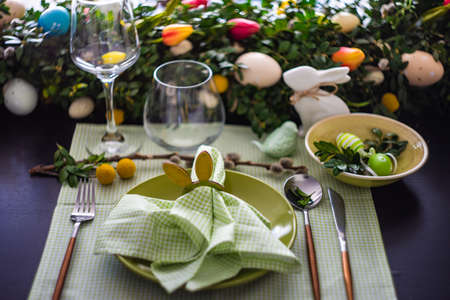 Festive table setting for Easter holiday dinner decorated with flowers and eggs