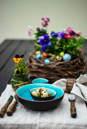 Festive table setting for Easter holiday dinner decorated with flowers and eggs