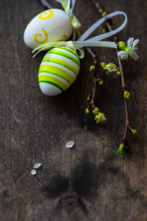 Easter holiday card concept with cherry bloom and colored eggs on rustic background with copy space