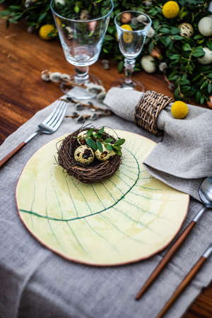 Festive table setting for Easter holiday dinner decorated with flowers and eggs