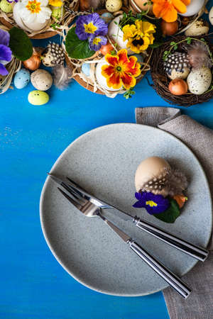 Festive table setting for Easter holiday dinner decorated with flowers and eggs