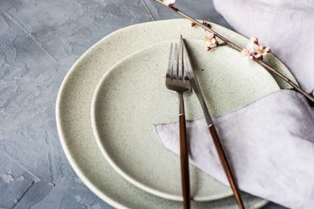 Spring floral concept with blooming cherry tree branches and serving with rustic tablewares on...