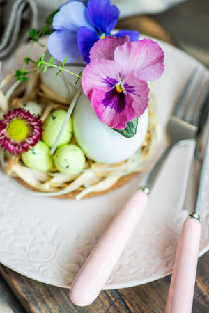 Festive table setting for Easter holiday dinner decorated with flowers and eggs