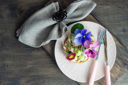 Festive table setting for Easter holiday dinner decorated with flowers and eggs