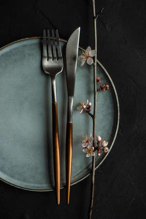 Spring floral concept with blooming cherry tree branches and serving with rustic tablewares on concrete tableの写真素材