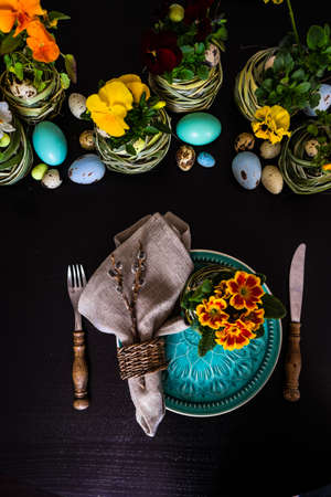 Festive table setting for Easter holiday dinner decorated with flowers and eggs