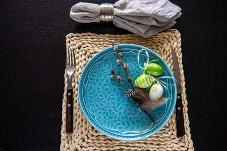 Festive table setting for Easter holiday dinner decorated with flowers and eggs