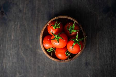 organic fresh cherry tomatoes in a bowl on rustic background with copy spaceの写真素材