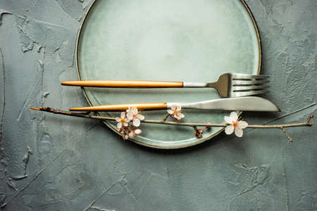 Spring floral concept with blooming cherry tree branches and serving with rustic tablewares on concrete tableの写真素材