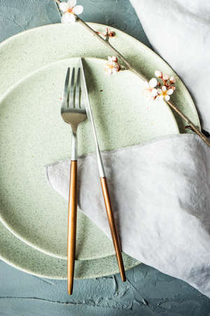 Spring floral concept with blooming cherry tree branches and serving with rustic tablewares on...