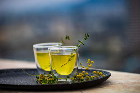 Traditional italian lemon alcohol drink limoncello with pieces of lemon and rosemary herb on dark wooden tableの写真素材