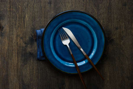 Rustic table setting with ceramic plates and modern cutlery on dark background with copy spaceの写真素材
