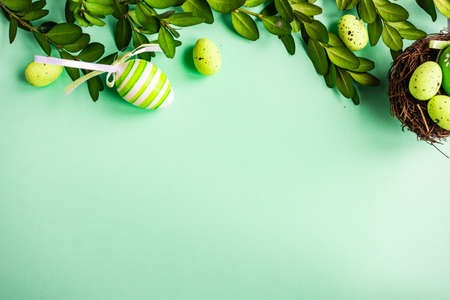 Easter holiday card concept with green colored eggs and boxwood on pastel green backgroundの写真素材