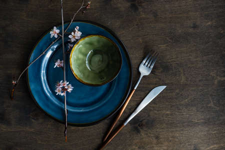 Spring table setting with peach blooming tree branch on wooden background with copy space