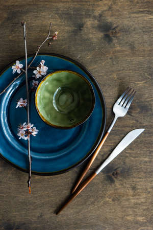 Spring table setting with peach blooming tree branch on wooden background with copy spaceの写真素材